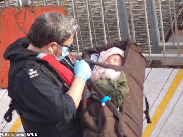 A tiny baby was spotted yesterday morning arriving in Dover with its family after crossing the Channel in a dinghy - carried in what appears to be a gym bag