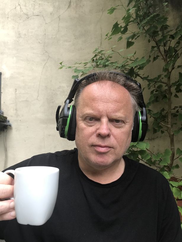 Freelance journalist Tim Newark wearing headphones to cancel out gull noise as he tries to relax with a cup of coffee in his backyard