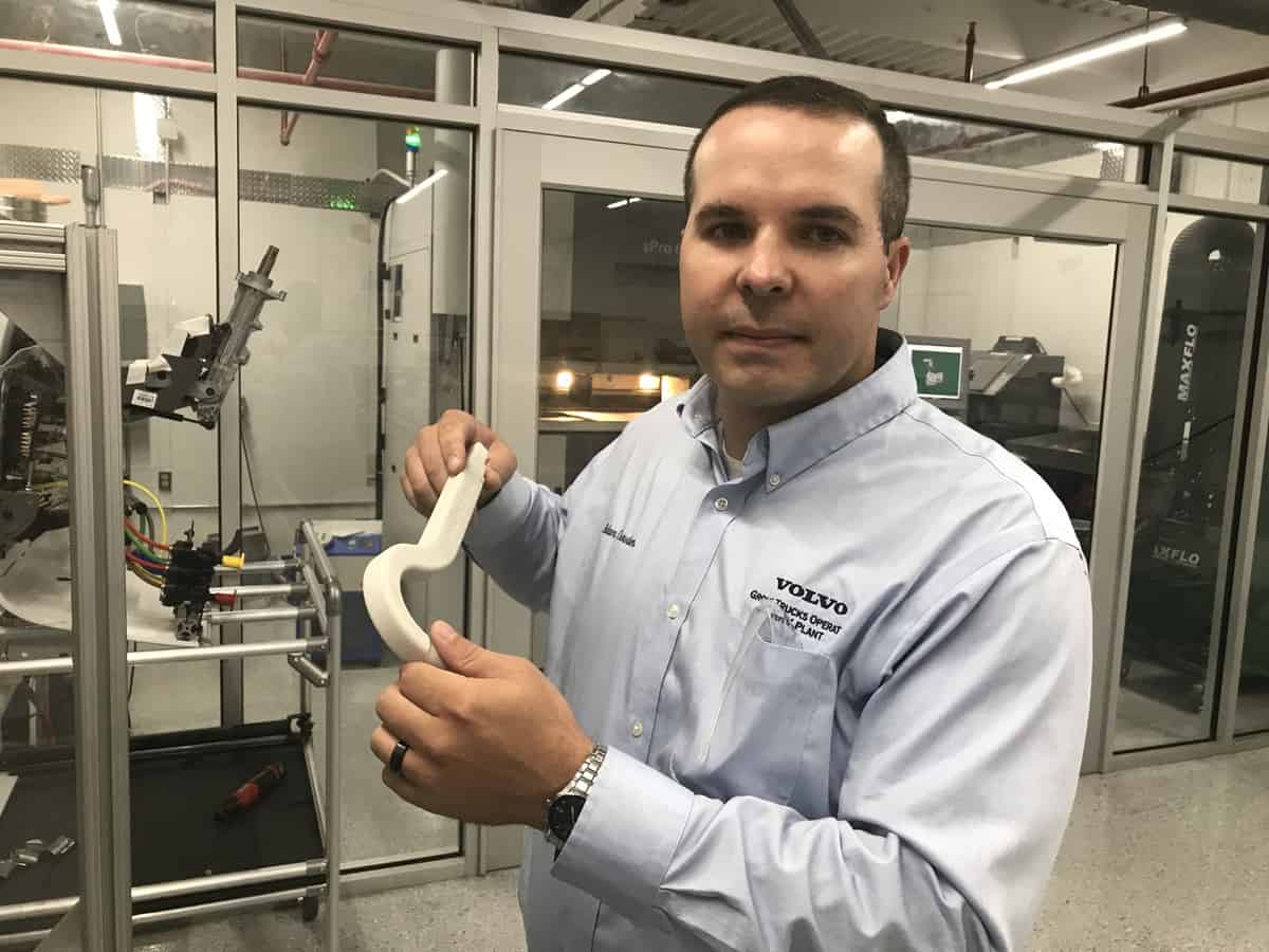 Adam Crowder holds a 3D-printed hook that Volvo Trucks uses to open truck doors before painting.