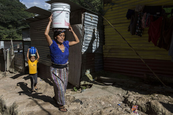 A woman and her daughter carry buckets of water to their home in the Dios es Fiel settlement, in Guatemala City. This community of some 85 families has lacked drinking water since it emerged eight years ago, depending only on a spring that provides water only during certain times of the year. (AP Photo/Oliver de Ros)