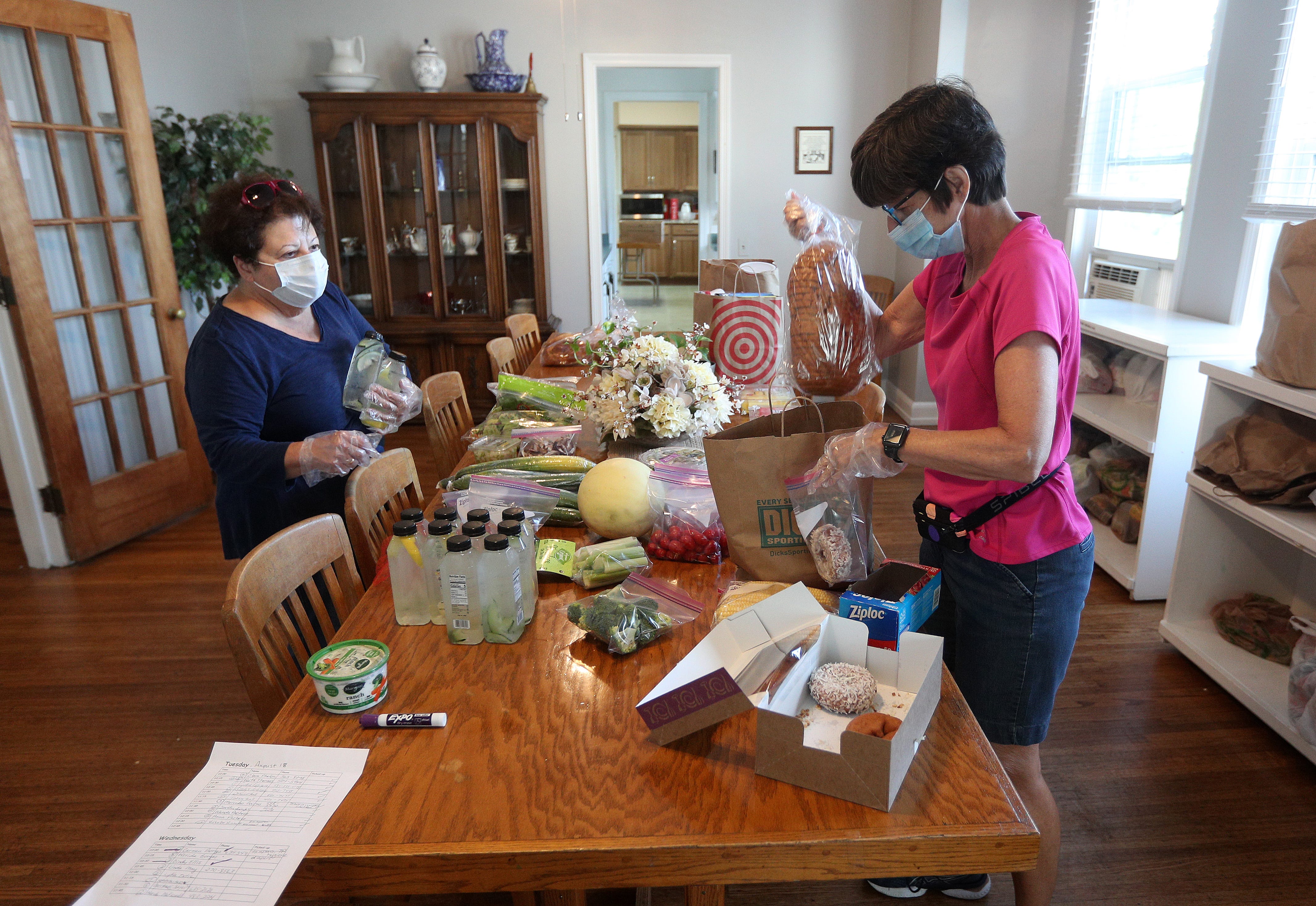 Volunteers Nancy Dining-Ferraro (L) and Janice Sengillo, pack groceries in the dining room at Bethany House.
