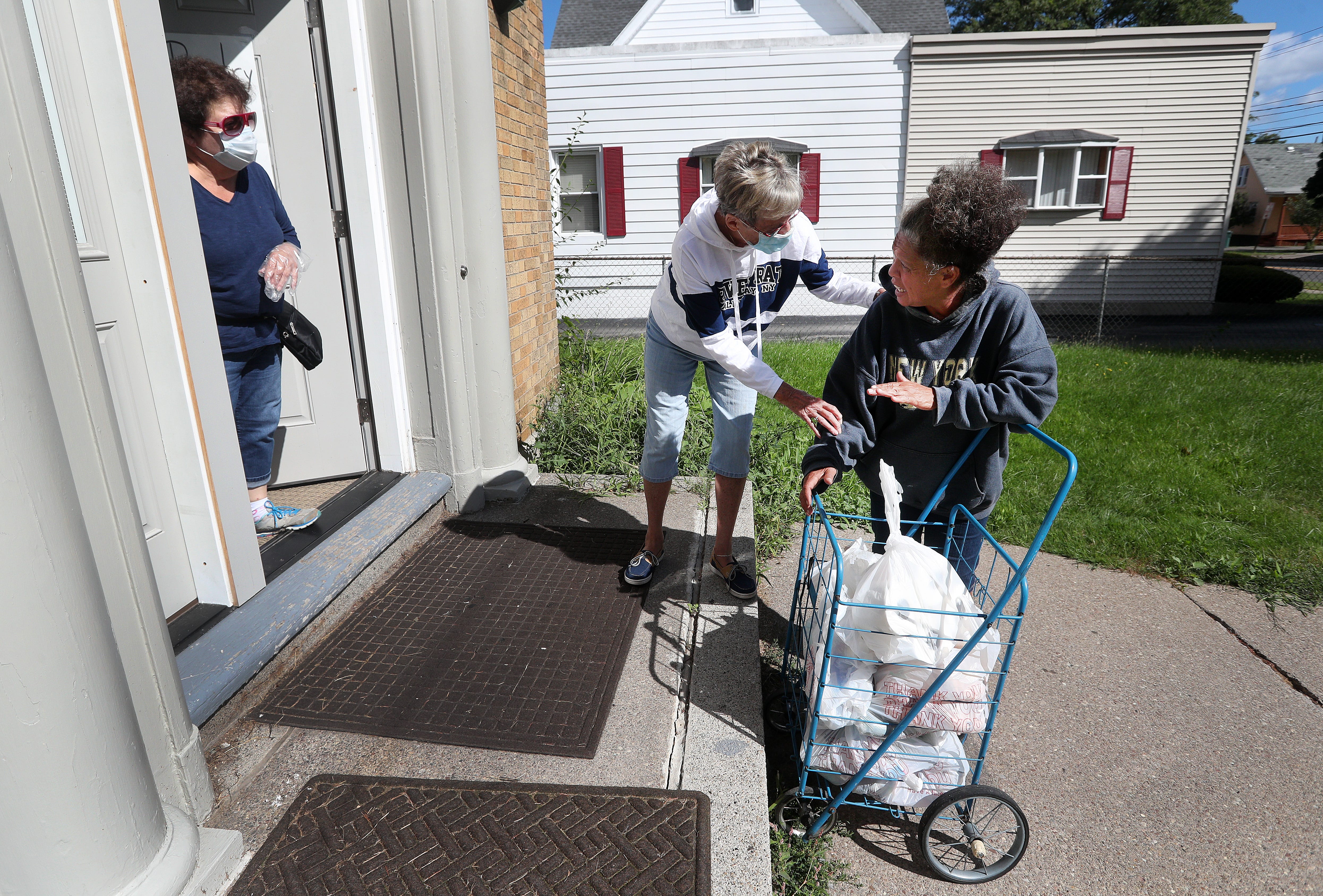 Ava Vazquez receives food and other grocery items  by volunteers Nancy Dinino-Ferraro (L) and Kathy Kanealey at Bethany House.