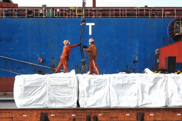 Workers upload plywood that will be exported on a cargo ship at a port in...