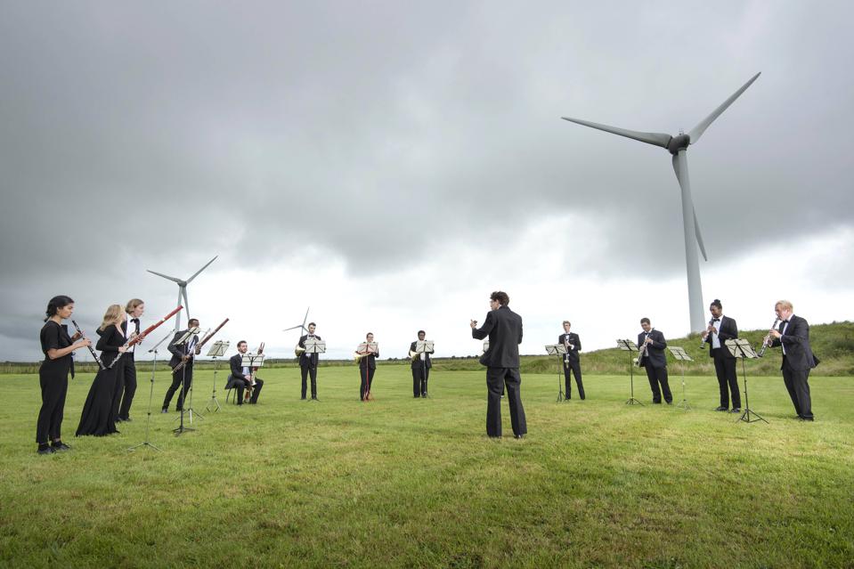 A 13-piece wind ensemble from Orchestra for the Earth performs at a wind farm in England.