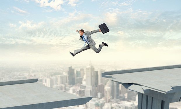 An image of a man holding a suitcase leaping over a gap in a raised roadway.