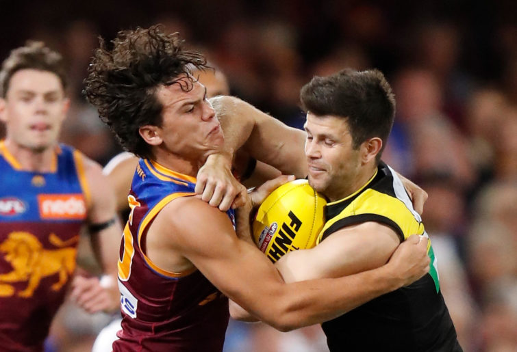 Trent Cotchin of the Tigers is tackled by Cam Rayner of the Lions