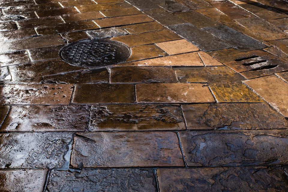 Wet old stone-paved flooring in Plaça del Pi (Pine Square), Barcelona, Spain.