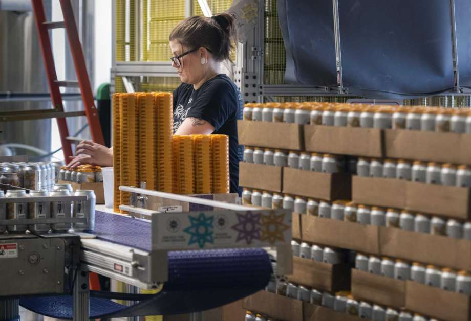 Brittany Zaborniak, a server at Cosmic Eye Brewing, stacks a tower of beers on the canning operation line, Friday, Aug. 21, 2020, in Lincoln, Neb. The Brewers Association warned at the end of July that aluminum can manufacturers were at capacity with no way to increase production this year. (Justin Wan/Lincoln Journal Star via AP) Photo: Justin Wan, MBI / Associated Press / LINCOLN JOURNAL STAR