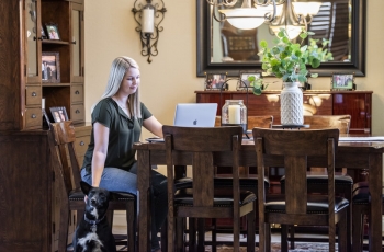 Woman at home on computer petting her dog