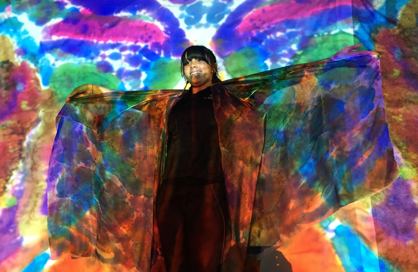 A girl standing in front of colourful backdrop.