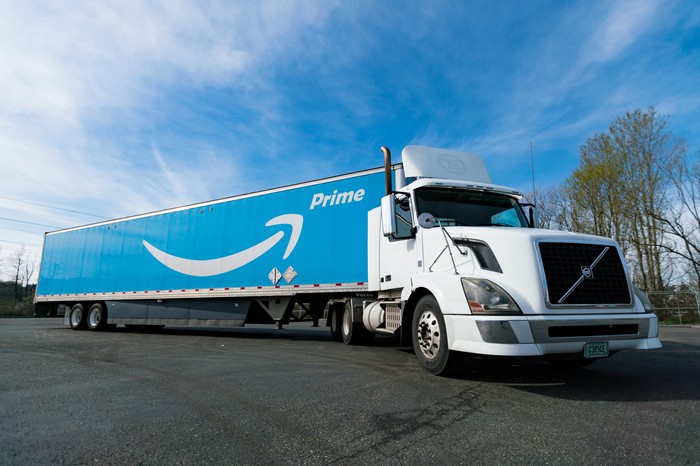 An Amazon truck with a white cab and a Prime logo on its side, under a sunny sky.
