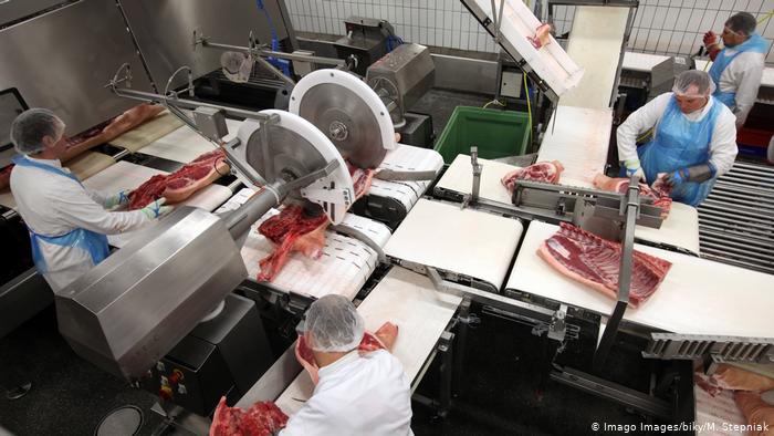Workers using machines to cut meat at a Tönnies slaughterhouse in Germany Workers using machines to cut meat at a Tönnies slaughterhouse in Germany