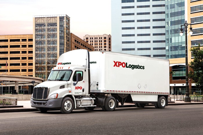 An XPO truck driving on a city street.