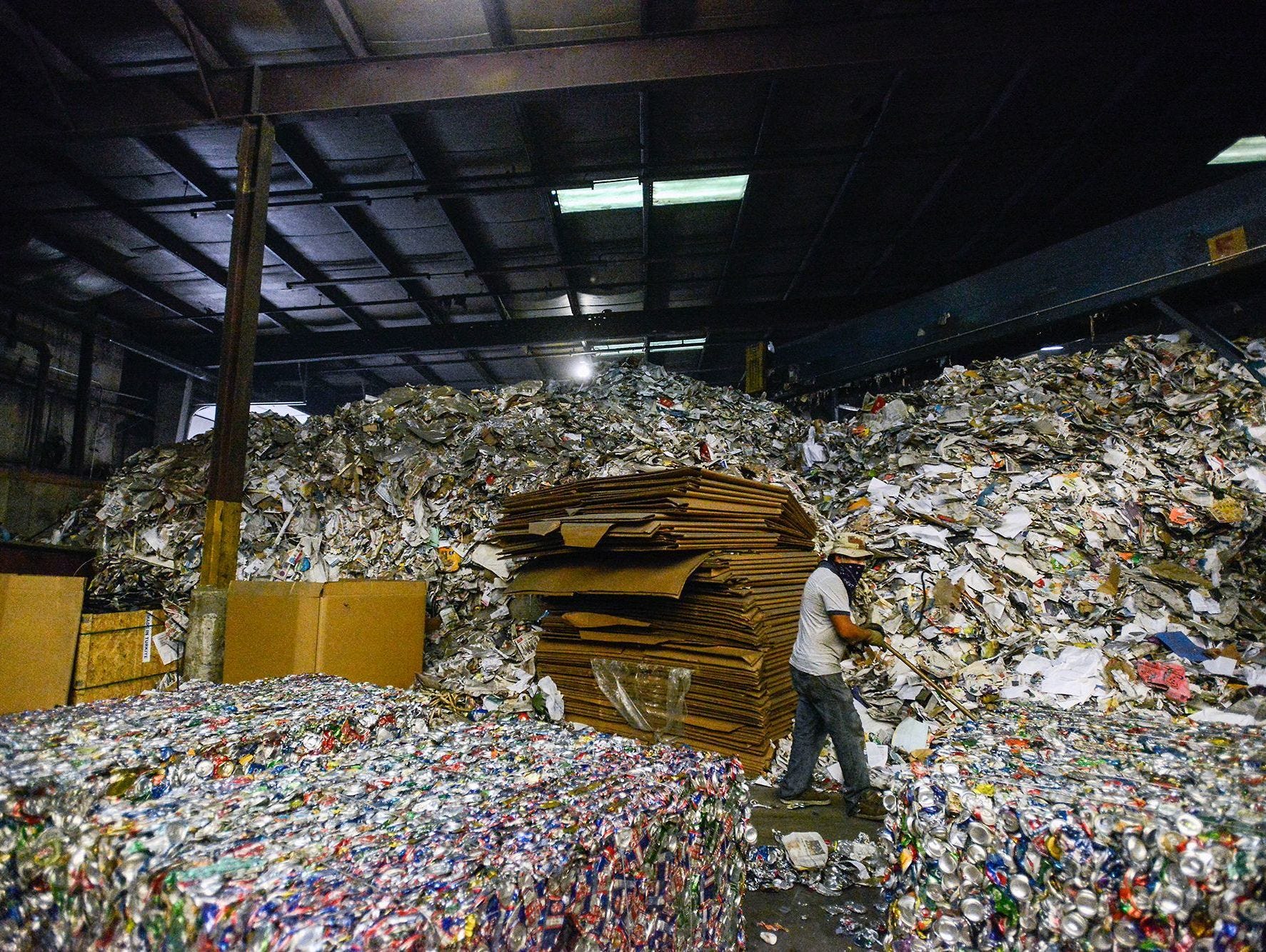 In this file photo, Jose Ramos pushes crushed cans off the floor inside the Curbside Management recycling center in Woodfin. Curbside Management, or Curbie, handles recycling for the city of Asheville and its 30,000 customers, as well as for Fletcher, Woodfin and Weaverville.