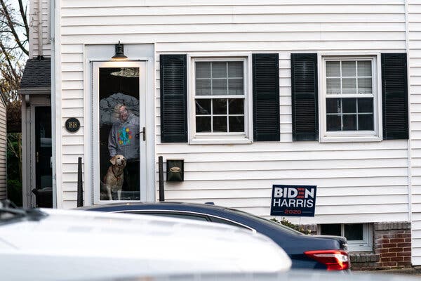 A woman watched from her house as President-elect Joseph R. Biden attended St. Ann’s Church in Wilmington, Del. Mr. Biden has transformed the city into a federal-government-in-waiting.