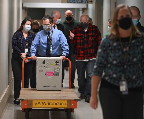 Gov. Tim Walz of Minnesota, right, followed the delivery of Covid-19 vaccines at the Minneapolis Veteran Affairs Hospital on Monday.