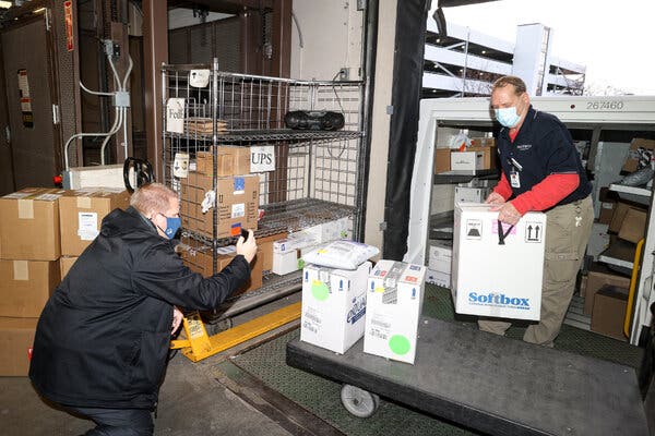 Tim Ostgarden, right, unloaded a carton of Covid-19 vaccine doses on Monday at Sanford Health in Fargo, N.D. as Nathan Aamodt photographed the arrival.