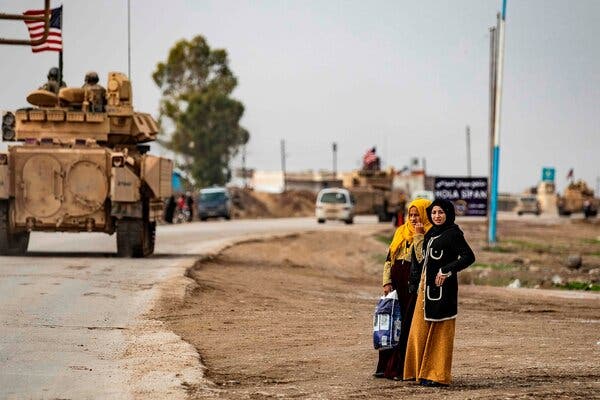 Women watched U.S. troops patrol the roads of the northeastern Syrian town of Al Jawadiyahin, near the border with Turkey, on Thursday. The coronavirus is surging in Syria, which has little capacity to cope with another crisis.