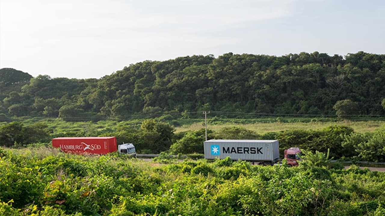 A truck carrying a Hamburg Süd-branded container follows another truck hauling a Maersk-branded container.
(Photo: A.P. Møller - Mærsk)
