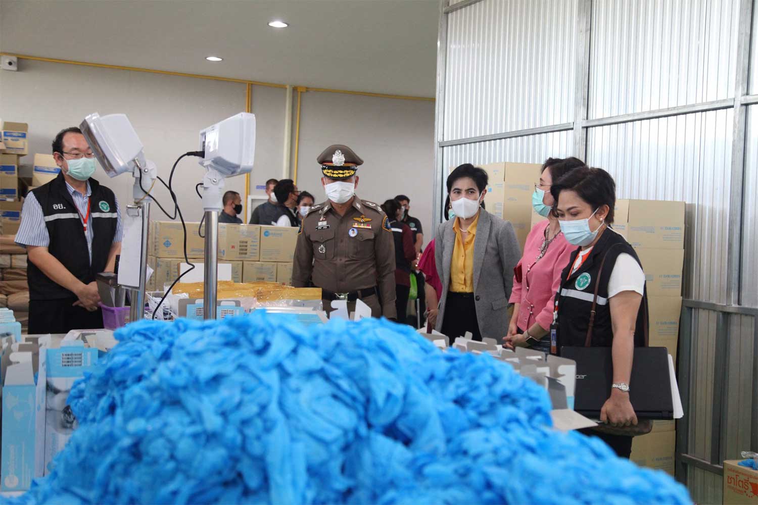 Crime Suppression Division police and other officials seize over 7 million medical gloves for examination during a raid on an illegal factory in Pathum Thani province on Saturday. A Chinese man, claiming to be the owner, and 11 Cambodian migrant workers, all without entry documents, are caught. (Crime Suppression Division photo)