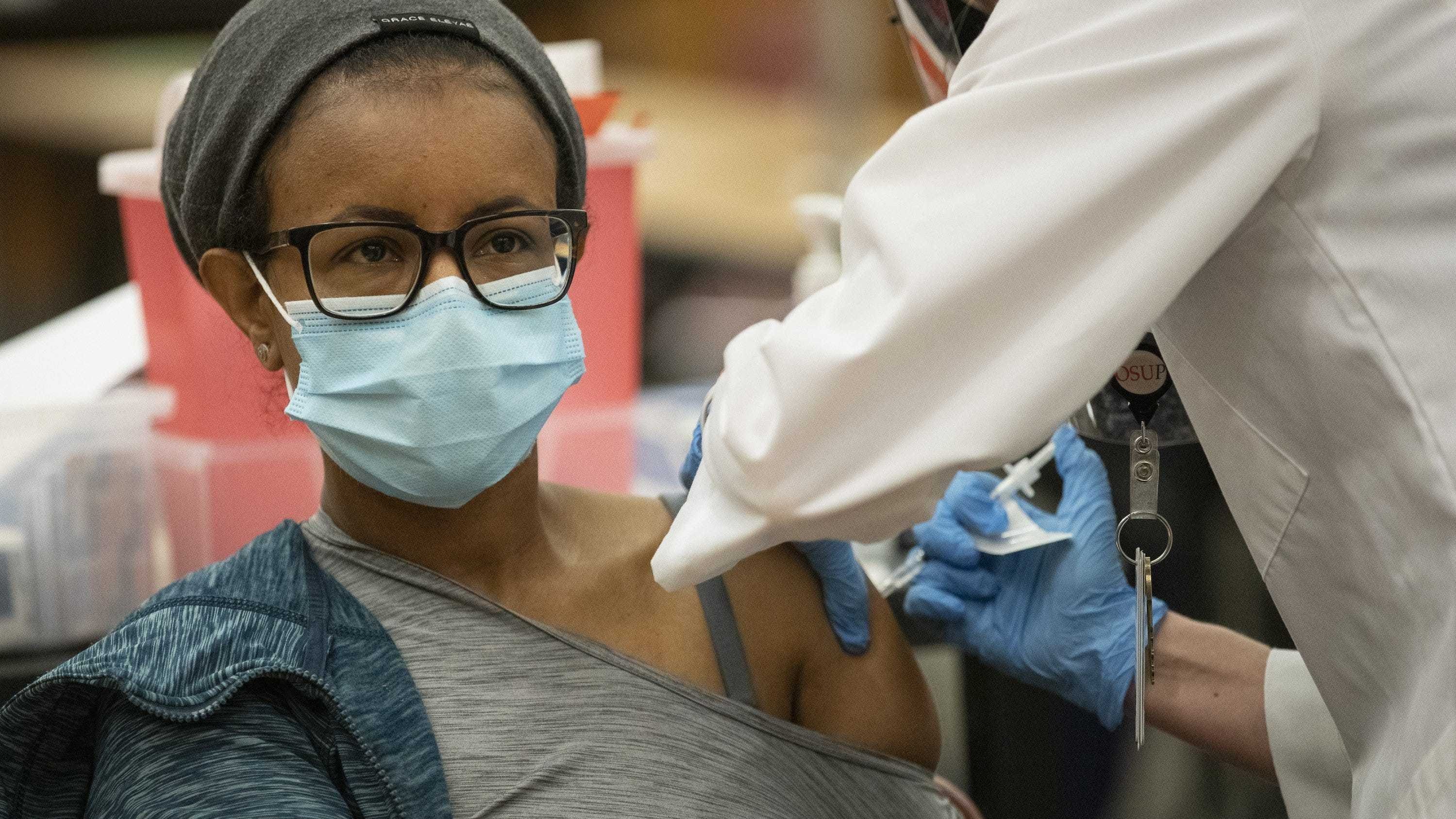 Dr. Rishan Desta, a resident emergency department physician, receives the COVID-19 vaccine from pharmacist Cory Coffey at Ohio State University's Wexner Medical Center on Monday.