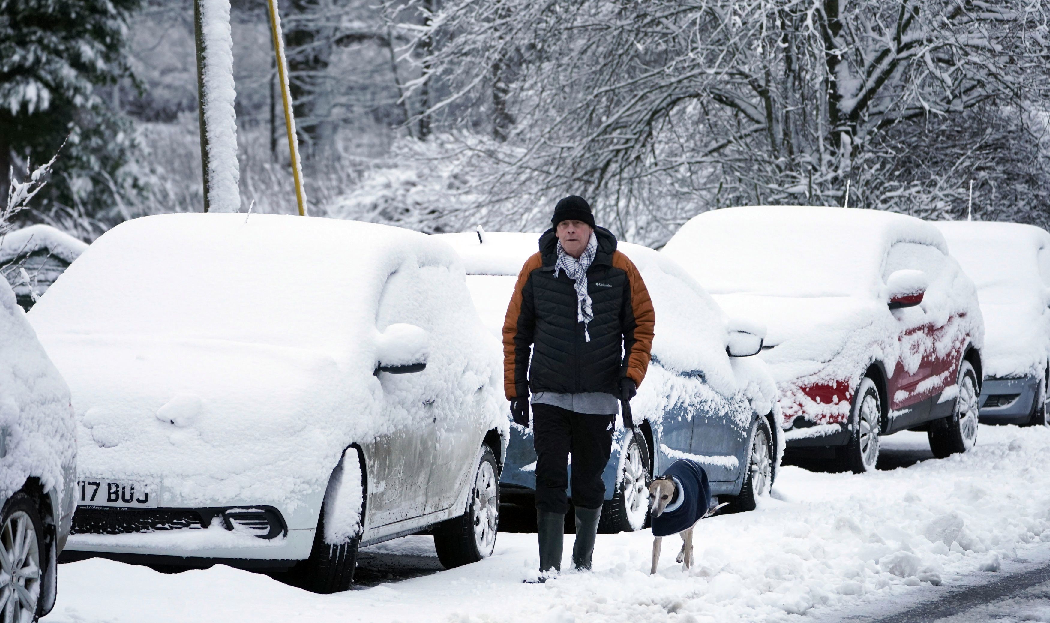 A man walks his dog through snow-covered roads this morning in Allenheads, Northumberland