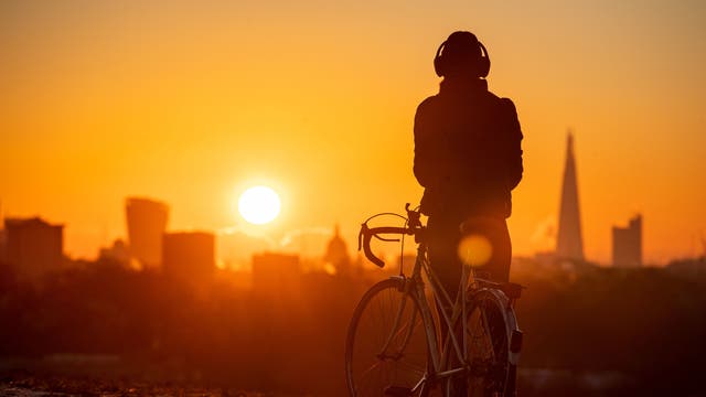 A cyclist watches the sun rise from Primrose Hill