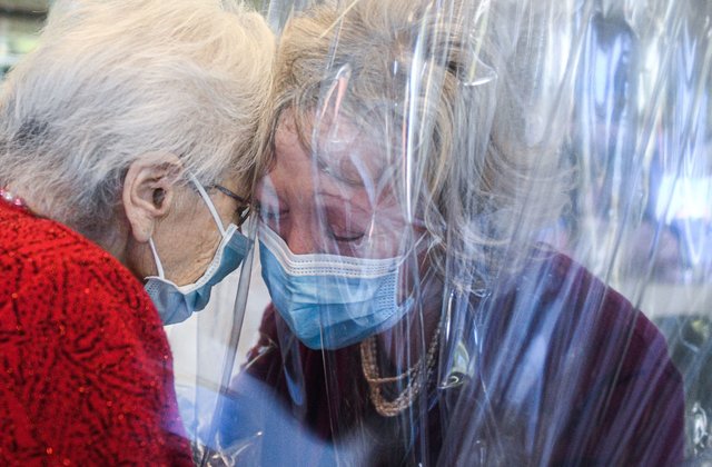 TOPSHOT - A resident (L) of the Domenico Sartor nursing home in Castelfranco Veneto, near Venice, hugs her visiting daughter on November 11, 2020 through a plastic screen in a so-called "Hug Room" amid the new coronavirus pandemic. - The Hug Room allows guests and their families to embrace each other, while remaining separate and protected from the contagious disease, still guaranteeing physical contact for mental and emotional wellbeing. (Photo by Piero CRUCIATTI / AFP) (Photo by PIERO CRUCIATTI/AFP via Getty Images)