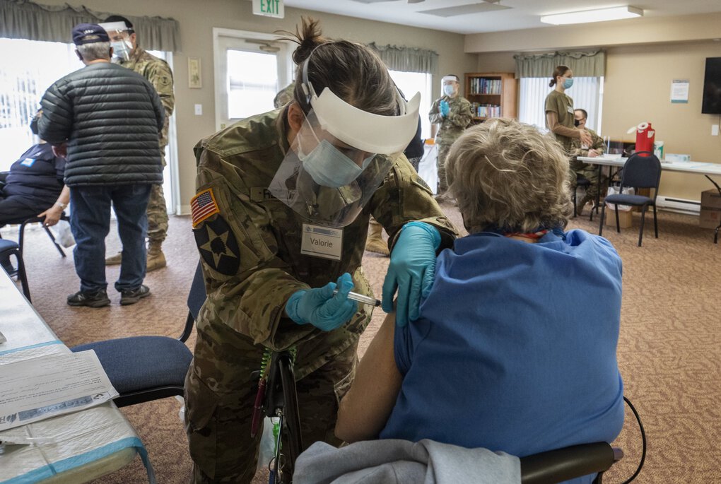 National Guard combat medic Valorie Reed gives a Lakewood Meadows resident a shot of Moderna’s COVID-19 vaccine Wednesday. About 150 members of the National Guard are supporting the Washington state Department of Health’s vaccine efforts through their work at four mass-vaccination sites and one mobile clinic. (Ellen M. Banner / The Seattle Times)