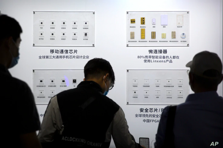 FILE - People look at semiconductors made by Tsinghua Unigroup on display at the China Beijing International High Tech Expo in Beijing, Sept. 19, 2020. 