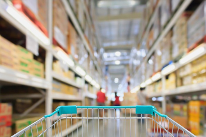 A shopping cart in the aisle of a wholesale retailer's store.