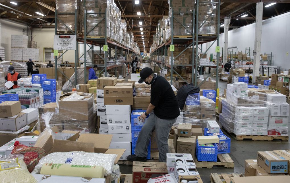 At Merlino Foods, a supplier to Western Washington restaurants, Charles Santa Cruz organizes pallets before loading his truck for delivery. Santa Cruz, a delivery driver at Merlino for more than four years, said part of his job lately is apologizing and explaining to customers about supply disruptions. (Ken Lambert / The Seattle Times)