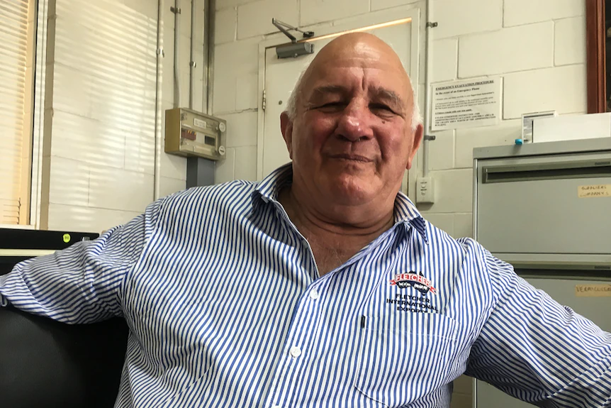 An older man in a button-up shirt leaning back in a chair.