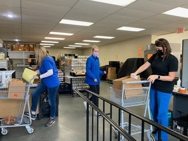 People move boxes and shopping carts around a workspace.