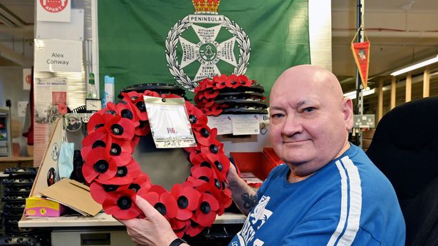 Poppy Factory worker Alex Conway holds up a wreath
