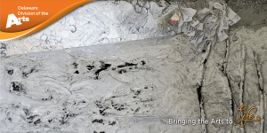 Delaware Division of the Arts logo on an orange banner in the upper left corner and Bringing the Arts to Life in the lower right corner over Denise Eno Ernest's painting Prayer Tree In The Bleak Mid-Winter 2021 - a canvas covered in thick white paint mixed with silver flakes to give it a silver sheen in addition to black and grey paints with tree branches attached on the right hand side of the canvas