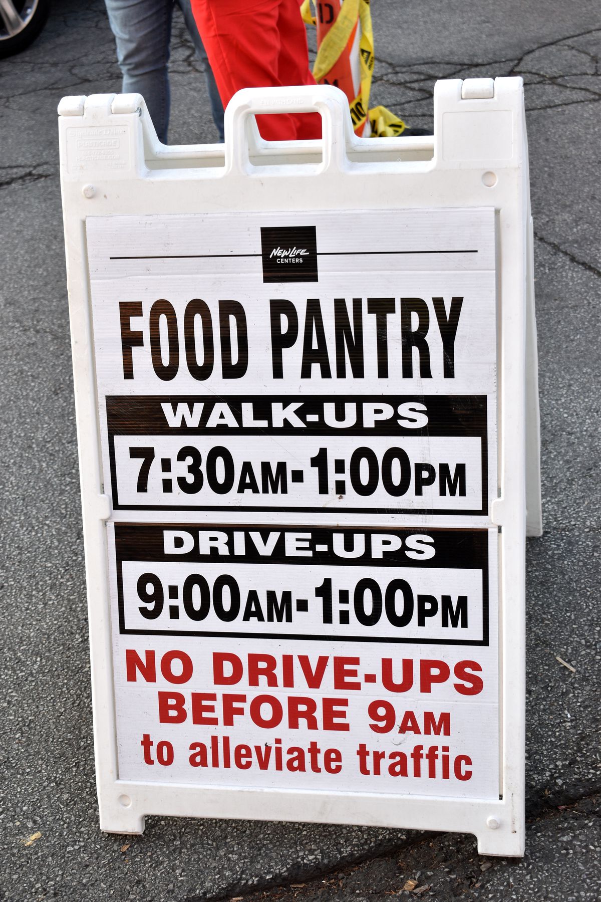 A sandwich board about walk-up and drive-up Pan De Vida food pantry hours.