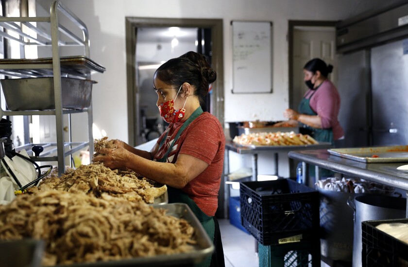 Josefina Pantoja shreds pork as Sylvia Uribe makes tamales at Tamaleria Maria's in Lynwood 