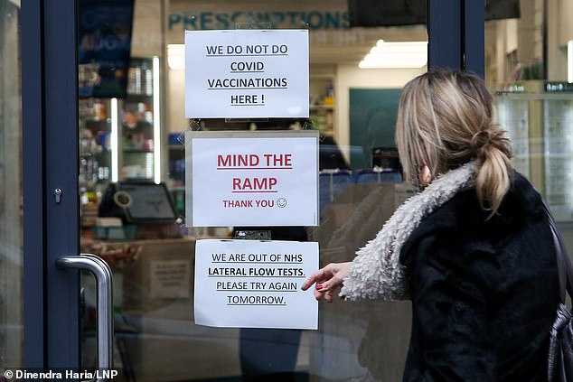 A woman points at a sign in the window of a pharmacy in North London on Saturday which has run out of lateral flow test kits