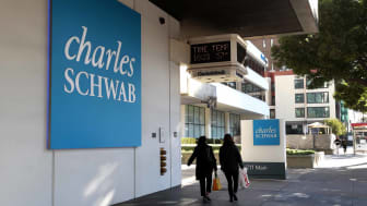 Two women walking by a Charles Schwab sign