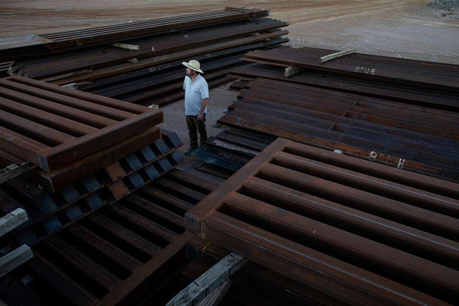 Myles Traphagen, Borderlands Program Coordinator at Wildlands Network, next to a pile of steel bollards left at a border wall construction site at the Guadalupe Canyon, Arizona. (Photograph by Adriana Zehbrauskas for The Atlantic)