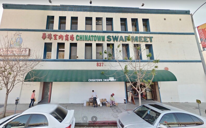 A screenshot of a 837 N. Spring St. when it was the Chinatown Swap Meet.  Pedestrians walk by a off-white building with green awnings and signs in English and Chinese.