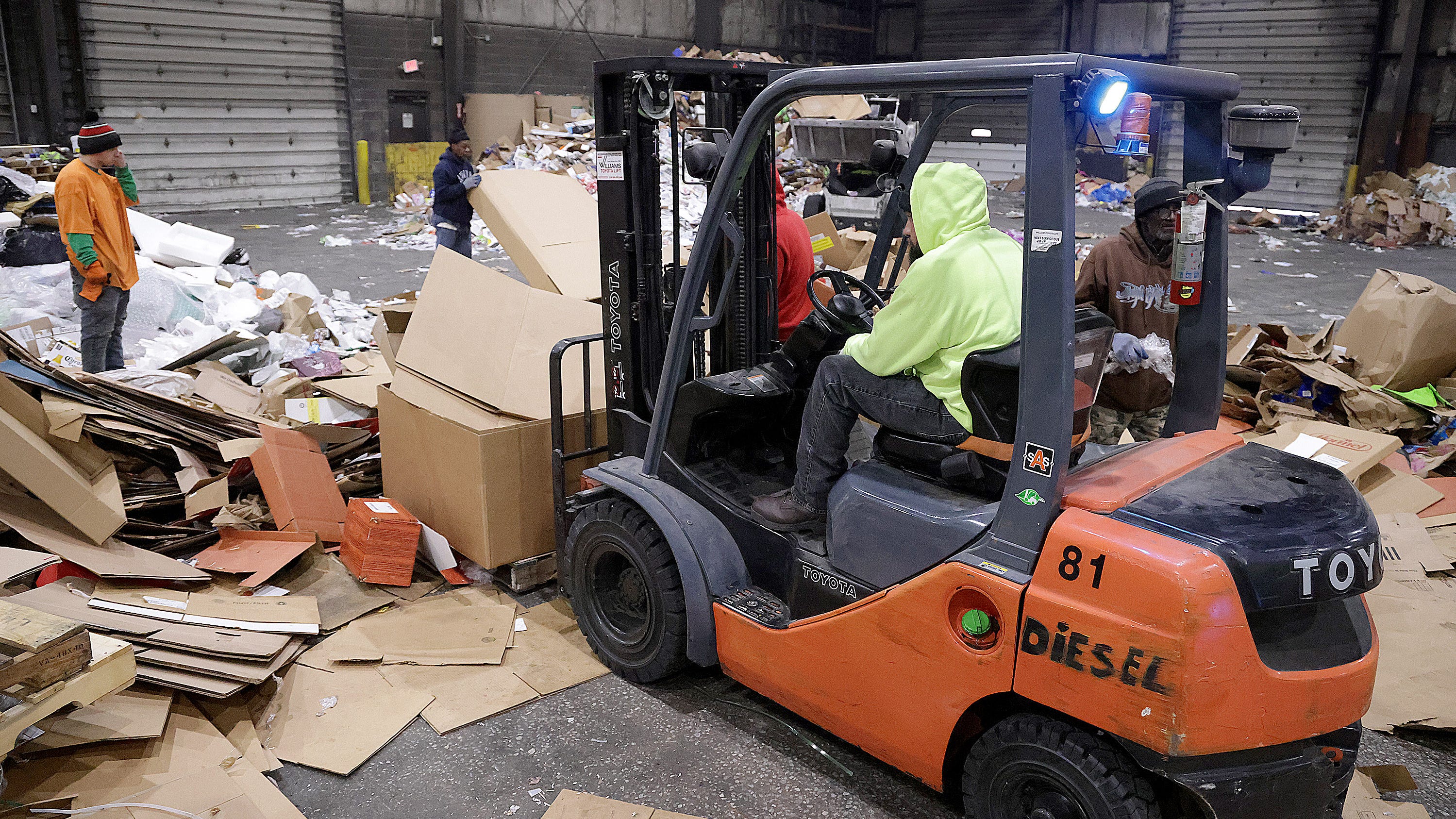 Workers at the S. Slesnick Recycling in Canton work to get as much cardboard gathered up so it may be sent to a facility to be recycled.