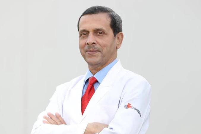 Professor Arvind Kumar stands folding his arms in a white doctor's coat. 