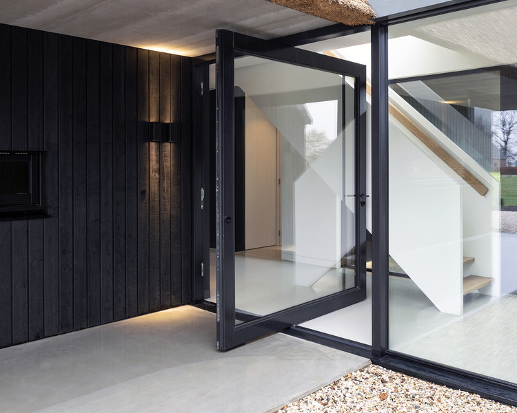 Copper colored frame on a glass exterior pivot door / Jeroen van Zwetselaar. Image Courtesy of FritsJurgens