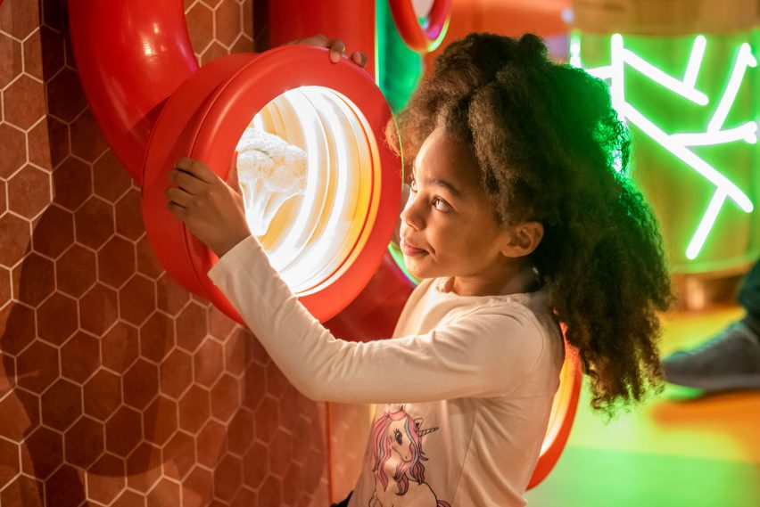 A child looking into a red tunnel