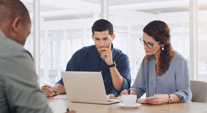 A group of people looking at a laptop.