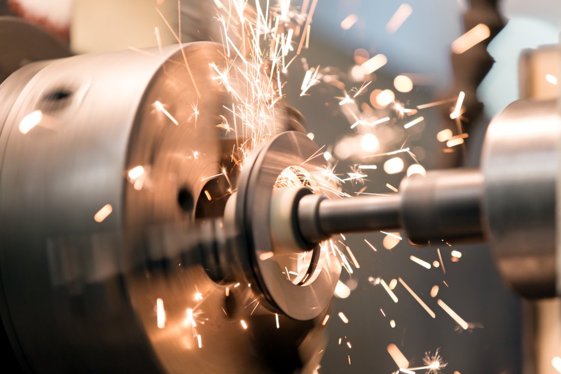 metalworking industry: finishing metal working internal steel surface on lathe grinder machine with flying sparks. Image courtesy of Shutterstock