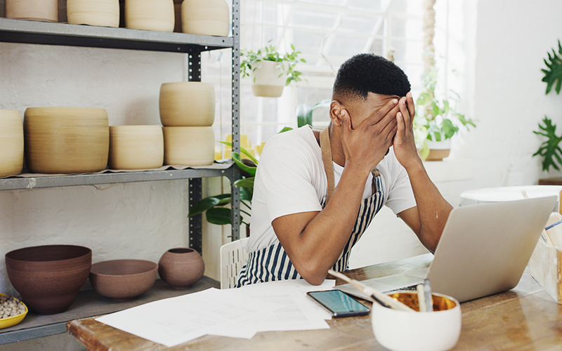 Shot of a stressed young man using a laptop while working in a ceramic studio
