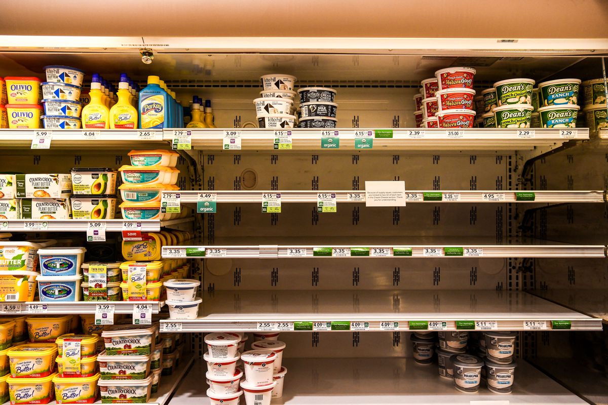 Butter and cheese shelves are seen empty at a supermarket.